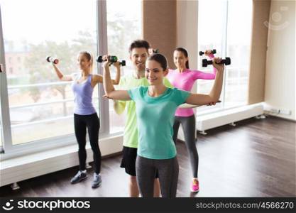 fitness, sport, training, gym and lifestyle concept - group of smiling people working out with dumbbells flexing muscles s in gym