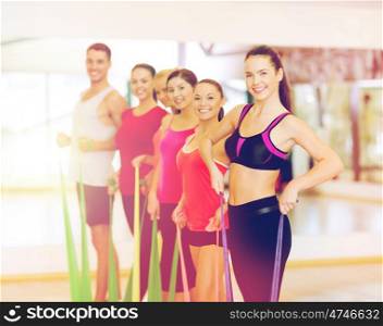 fitness, sport, training, gym and lifestyle concept - group of smiling people working out with rubber bands in the gym