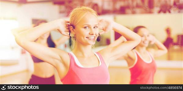 fitness, sport, training, gym and lifestyle concept - group of smiling people with trainer exercising in the gym