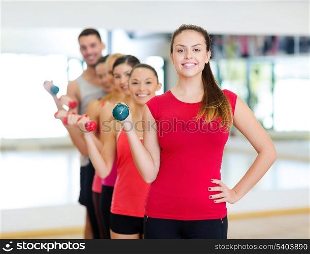 fitness, sport, training, gym and lifestyle concept - group of smiling people lifting dumbbells in the gym