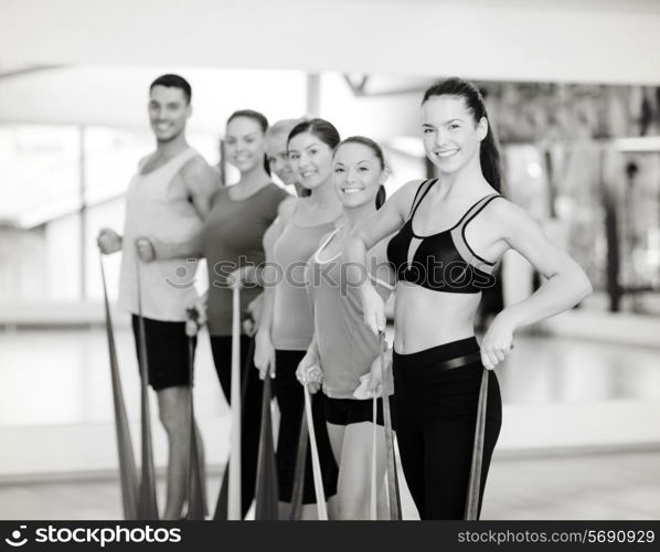 fitness, sport, training, gym and lifestyle concept - group of smiling people working out with rubber bands in the gym