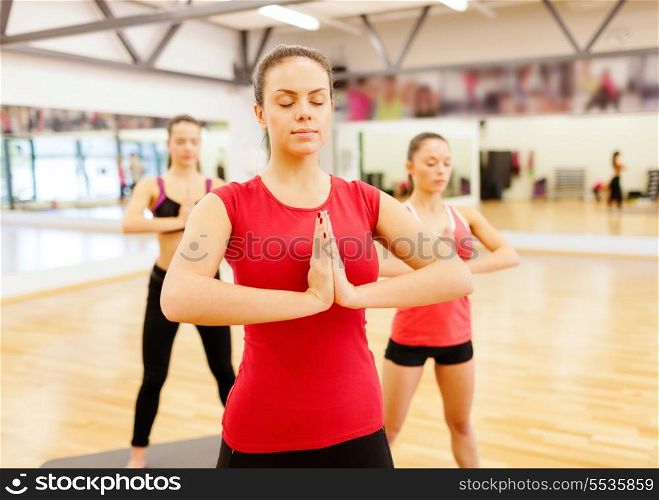 fitness, sport, training, gym and lifestyle concept - group of smiling people meditating in the gym