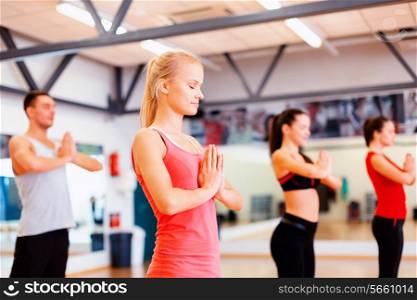 fitness, sport, training, gym and lifestyle concept - group of smiling people meditating in the gym