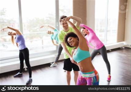 fitness, sport, training, gym and lifestyle concept - group of smiling people stretching in gym