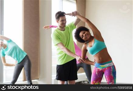 fitness, sport, training, gym and lifestyle concept - group of smiling people stretching in gym