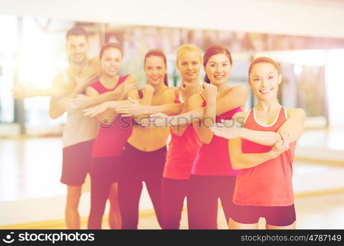 fitness, sport, training, gym and lifestyle concept - group of smiling people stretching in the gym