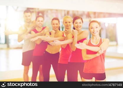 fitness, sport, training, gym and lifestyle concept - group of smiling people stretching in the gym