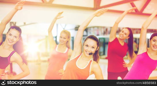 fitness, sport, training, gym and lifestyle concept - group of smiling people stretching in the gym