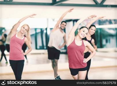 fitness, sport, training, gym and lifestyle concept - group of smiling people stretching in the gym