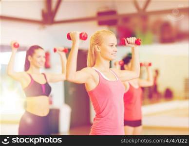 fitness, sport, training, gym and lifestyle concept - group of smiling women working out with dumbbells in the gym