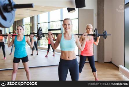 fitness, sport, training, gym and lifestyle concept - group of women excercising with bars in gym