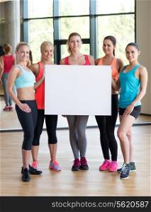 fitness, sport, training, gym and lifestyle concept - group of women witn white blank billboard in gym