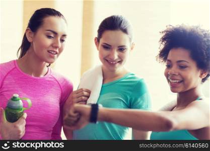 fitness, sport, training, gym and lifestyle concept - happy women showing time on wrist watch in gym