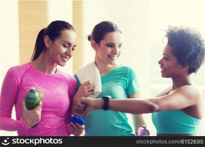fitness, sport, training, gym and lifestyle concept - happy women showing time on wrist watch in gym