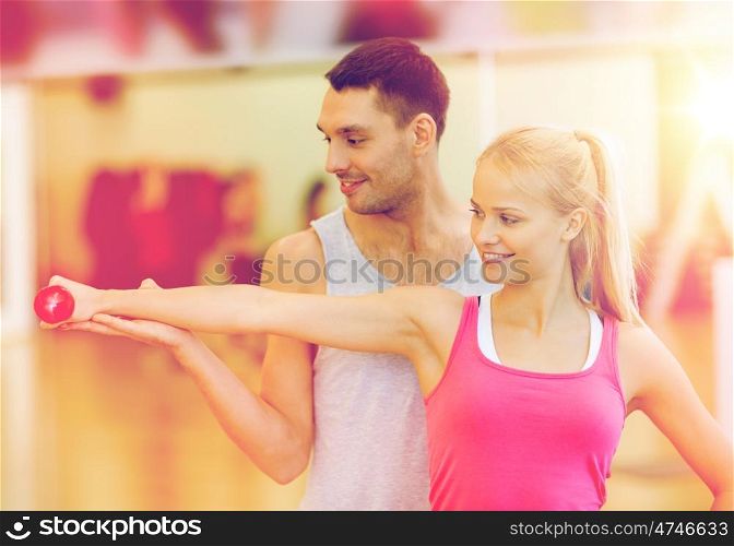 fitness, sport, training, gym and lifestyle concept - male trainer with woman working out with dumbbell