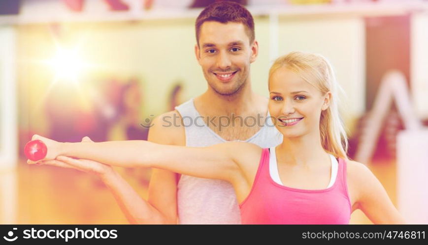 fitness, sport, training, gym and lifestyle concept - male trainer with woman working out with dumbbell