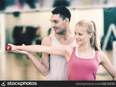 fitness, sport, training, gym and lifestyle concept - male trainer with woman working out with dumbbell