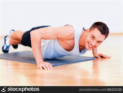 fitness, sport, training, gym and lifestyle concept - smiling man doing push-ups in the gym or at home
