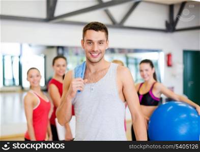 fitness, sport, training, gym and lifestyle concept - smiling man standing in front of the group of people in gym