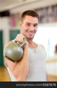 fitness, sport, training, gym and lifestyle concept - smiling man with kettlebell in gym