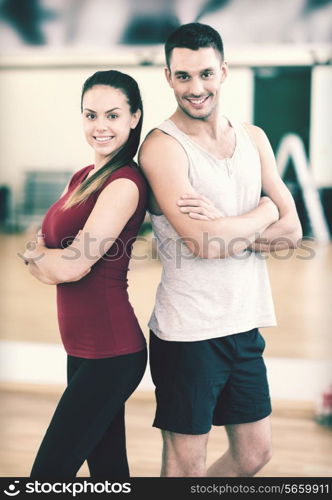 fitness, sport, training, gym and lifestyle concept - two smiling people in the gym