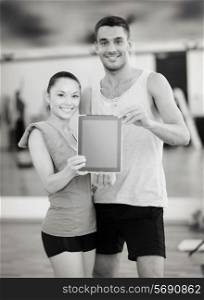 fitness, sport, training, gym and lifestyle concept - two smiling people showing blank tablet pc screen