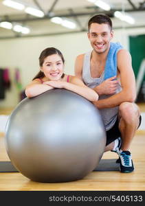 fitness, sport, training, gym and lifestyle concept - two smiling people with fitness ball in the gym