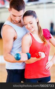 fitness, sport, training, gym and lifestyle concept - two smiling people working out with dumbbells in the gym