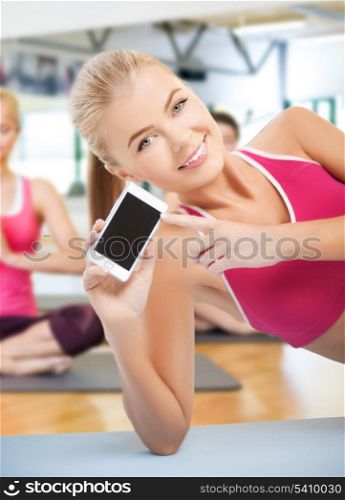 fitness, sport, training, gym and lifestyle concept - woman lying on the floor and sowing smartphone