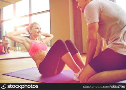 fitness, sport, training, gym and lifestyle concept - woman with personal trainer doing sit ups in gym