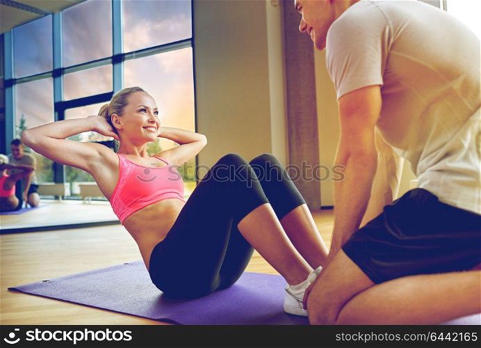 fitness, sport, training, gym and lifestyle concept - woman with personal trainer doing sit ups in gym. woman with personal trainer doing sit ups in gym