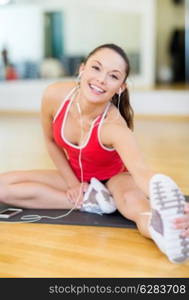 fitness, sport, training, gym, technology and lifestyle concept - smiling teenage girl with smartphone and earphones in gym