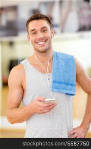 fitness, sport, training, gym, technology and lifestyle concept - young man with smartphone and towel in gym
