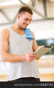 fitness, sport, training, gym, technology and lifestyle concept - young man with tablet pc computer and towel in gym