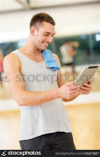 fitness, sport, training, gym, technology and lifestyle concept - young man with tablet pc computer and towel in gym