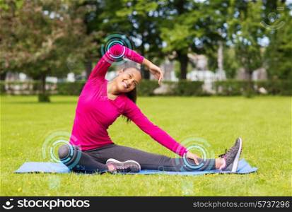fitness, sport, training, park and lifestyle concept - smiling woman stretching leg on mat outdoors