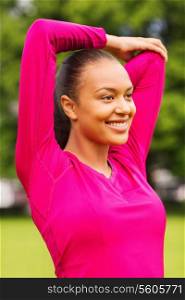 fitness, sport, training, park and lifestyle concept - smiling woman stretching leg outdoors