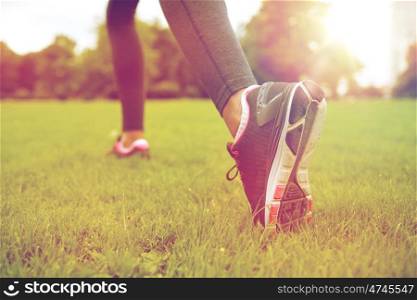 fitness, sport, training, people and lifestyle concept - close up of exercising woman legs on grass in park
