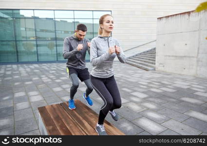 fitness, sport, training, people and lifestyle concept - couple making step exercise on city street bench