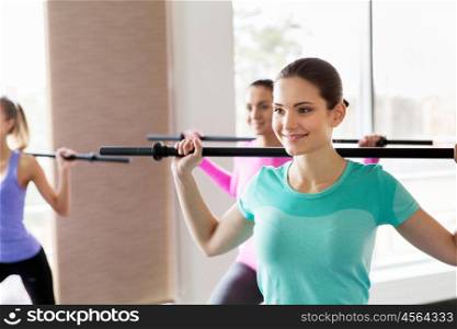 fitness, sport, training, people and lifestyle concept - group of happy women with bars exercising in gym