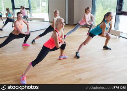 fitness, sport, training, people and lifestyle concept - group of women making lunge exercise in gym