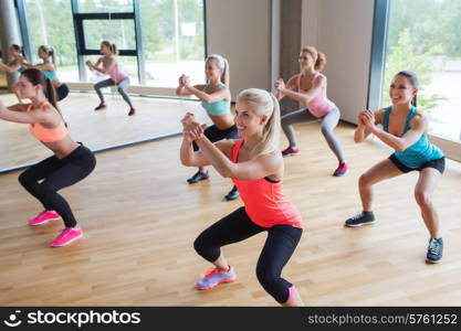 fitness, sport, training, people and lifestyle concept - group of women making squats in gym