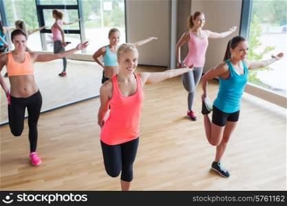 fitness, sport, training, people and lifestyle concept - group of women stretching leg in gym