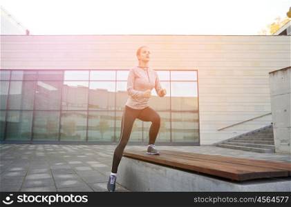 fitness, sport, training, people and lifestyle concept - young woman making step exercise on city street bench