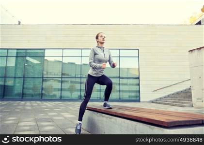 fitness, sport, training, people and lifestyle concept - young woman making step exercise on city street bench. woman making step exercise on city street bench