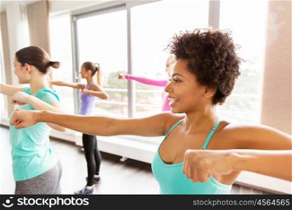 fitness, sport, training, people and martial arts concept - group of happy women working out fighting stance in gym