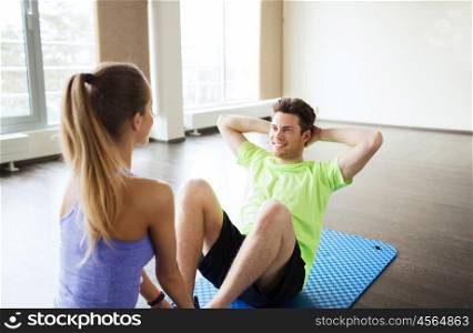 fitness, sport, training, teamwork and people concept - happy woman with personal trainer doing sit ups in gym