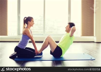 fitness, sport, training, teamwork and people concept - woman with personal trainer doing sit ups in gym