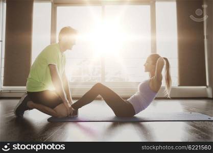 fitness, sport, training, teamwork and people concept - woman with personal trainer doing sit ups in gym