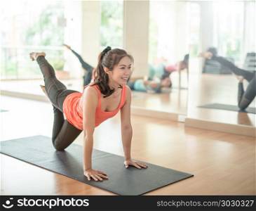 fitness, sport, training, yoga and people concept - Asian woman stretching in gym.Group Of female Doing Yoga Indoors